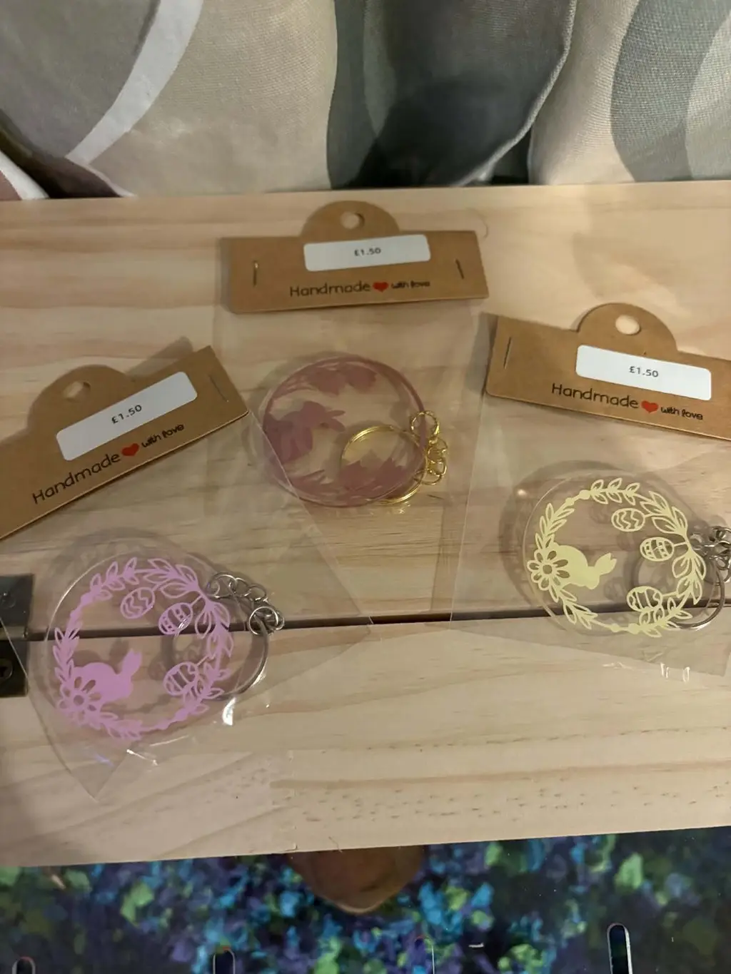 Three clear round keyrings with a bunny in a floral wreath, in pink, dusty rose and cream